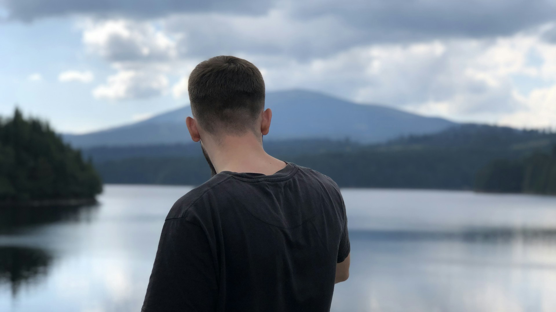 man in black crew neck t-shirt standing near body of water during daytime