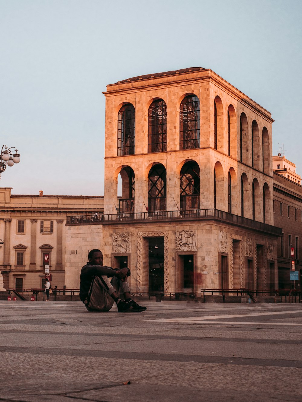 man in black jacket sitting on bench near building during daytime