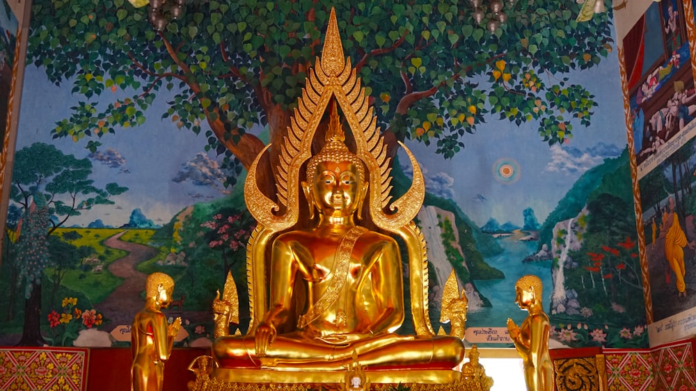 estatua de la deidad hindú de oro cerca de la pintura del árbol verde