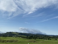 Wide-angle view of the golf course with rolling greens and a few houses tucked into the landscape.