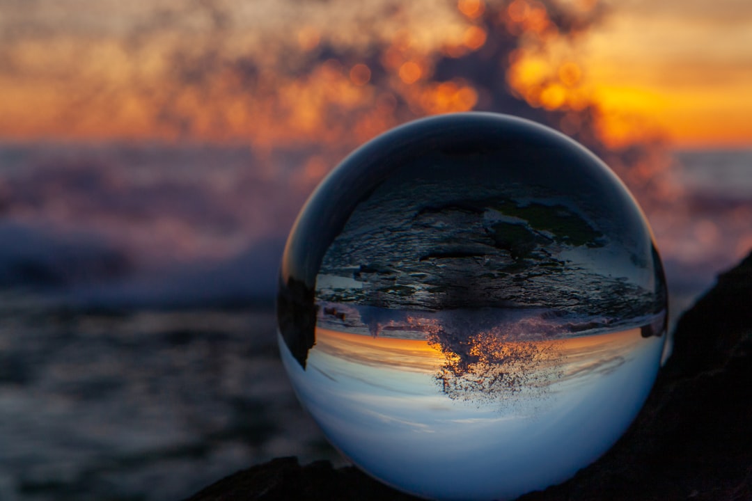 clear glass ball on black rock during sunset