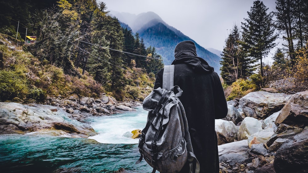 person in black hoodie standing near river during daytime