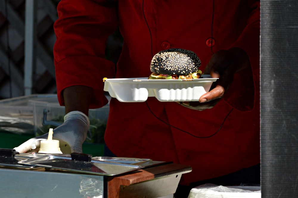 Persona che tiene la ciotola di ceramica bianca con il cibo