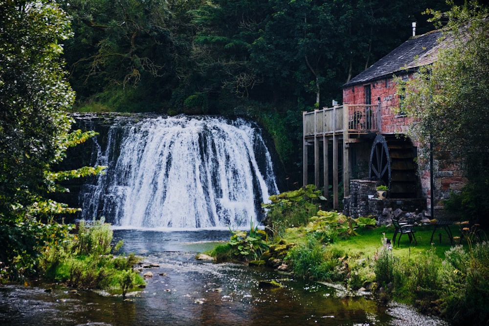 brown wooden house near waterfalls during daytime