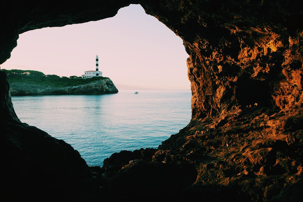 white lighthouse on brown rock formation near body of water during daytime