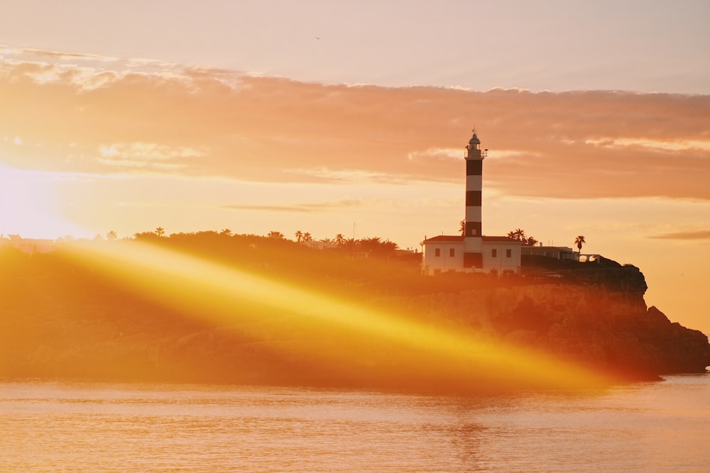 Weißer und schwarzer Leuchtturm in der Nähe des Gewässers bei Sonnenuntergang