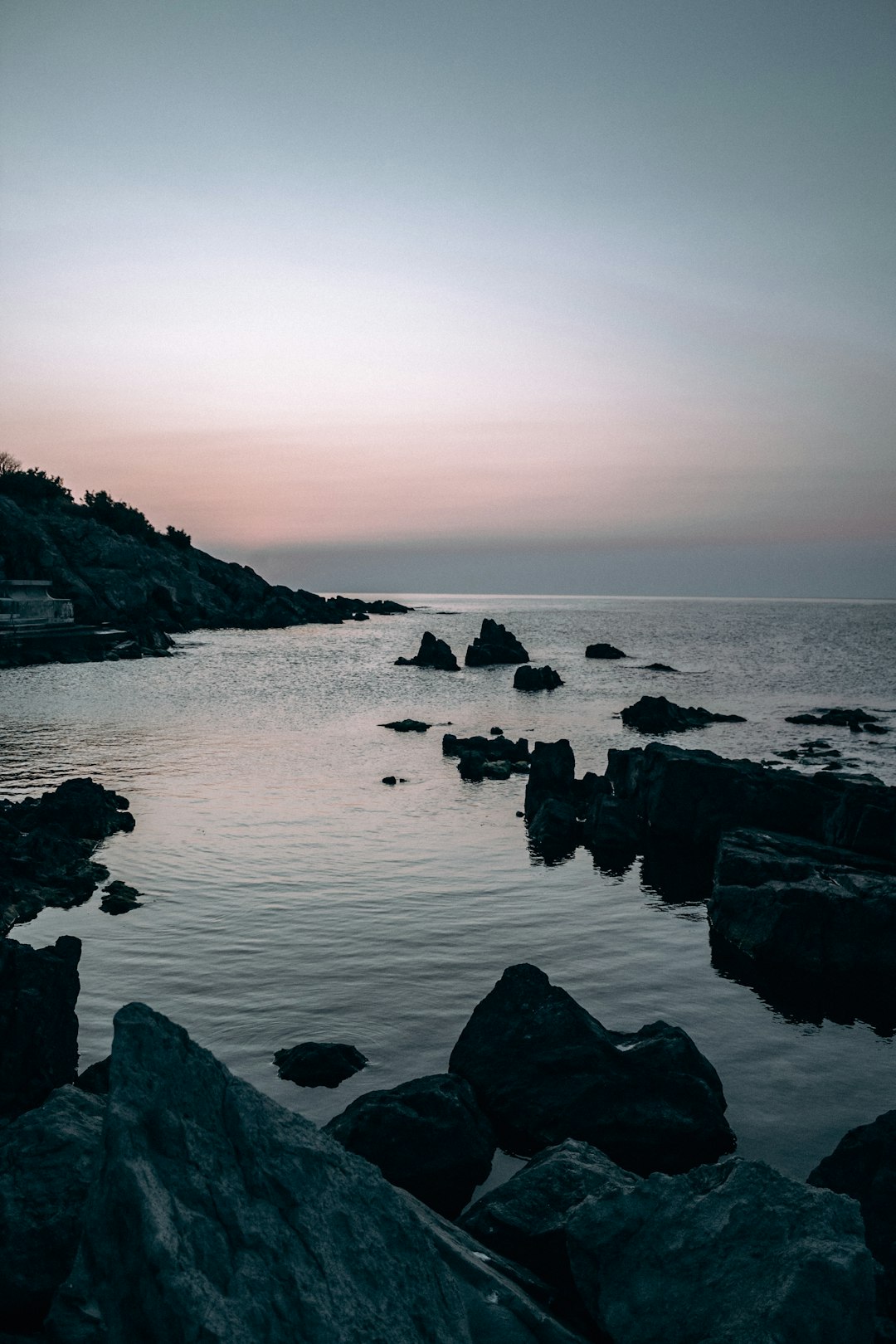 black rocks on body of water during daytime