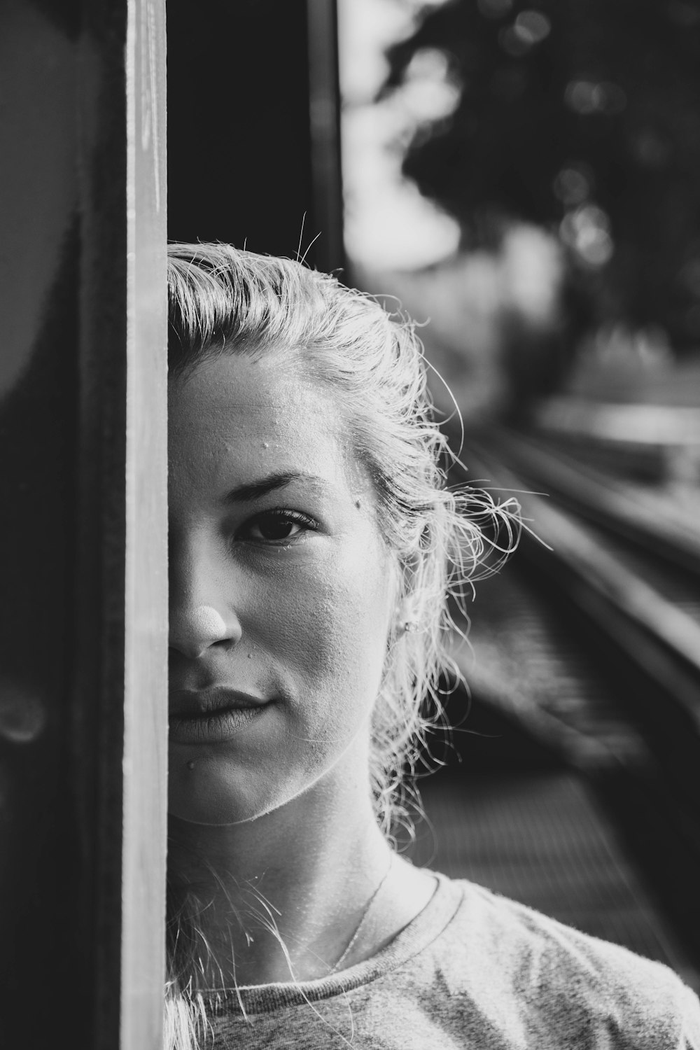 grayscale photo of woman looking out the window