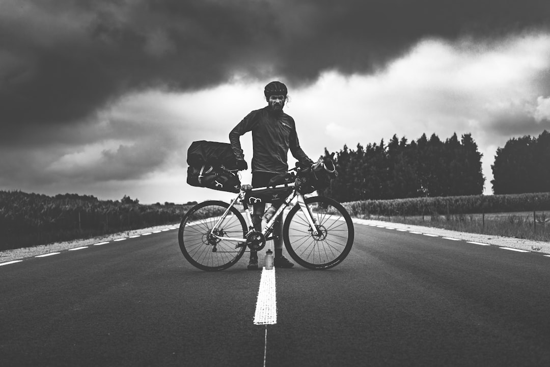 man in black jacket riding bicycle on road during daytime