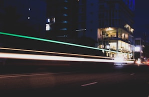 Nighttime cityscape with glowing streetlights and moving traffic, filmed from above.
