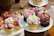 A colorful assortment of cupcakes with intricate floral icing designs arranged on a rustic wooden tray.
