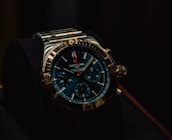 A luxury wristwatch with a metallic strap and a detailed, dark blue dial featuring multiple small dials and a prominently displayed brand name. The watch has a rugged yet elegant design with a polished metal case and intricate details on the crown and bezel.