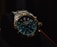 A luxury wristwatch with a metallic strap and a detailed, dark blue dial featuring multiple small dials and a prominently displayed brand name. The watch has a rugged yet elegant design with a polished metal case and intricate details on the crown and bezel.