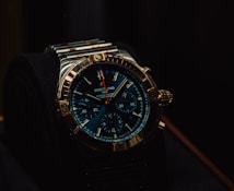 A luxury wristwatch with a metallic strap and a detailed, dark blue dial featuring multiple small dials and a prominently displayed brand name. The watch has a rugged yet elegant design with a polished metal case and intricate details on the crown and bezel.