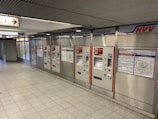 A row of ticket vending machines with the label 'Fahrkarten' in a subway station environment. The area is clean and well-lit, with metal paneling and informational maps and signage visible on the machines.