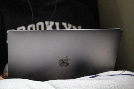 A traveler happily checking flight options on a laptop in a cozy Brooklyn apartment.