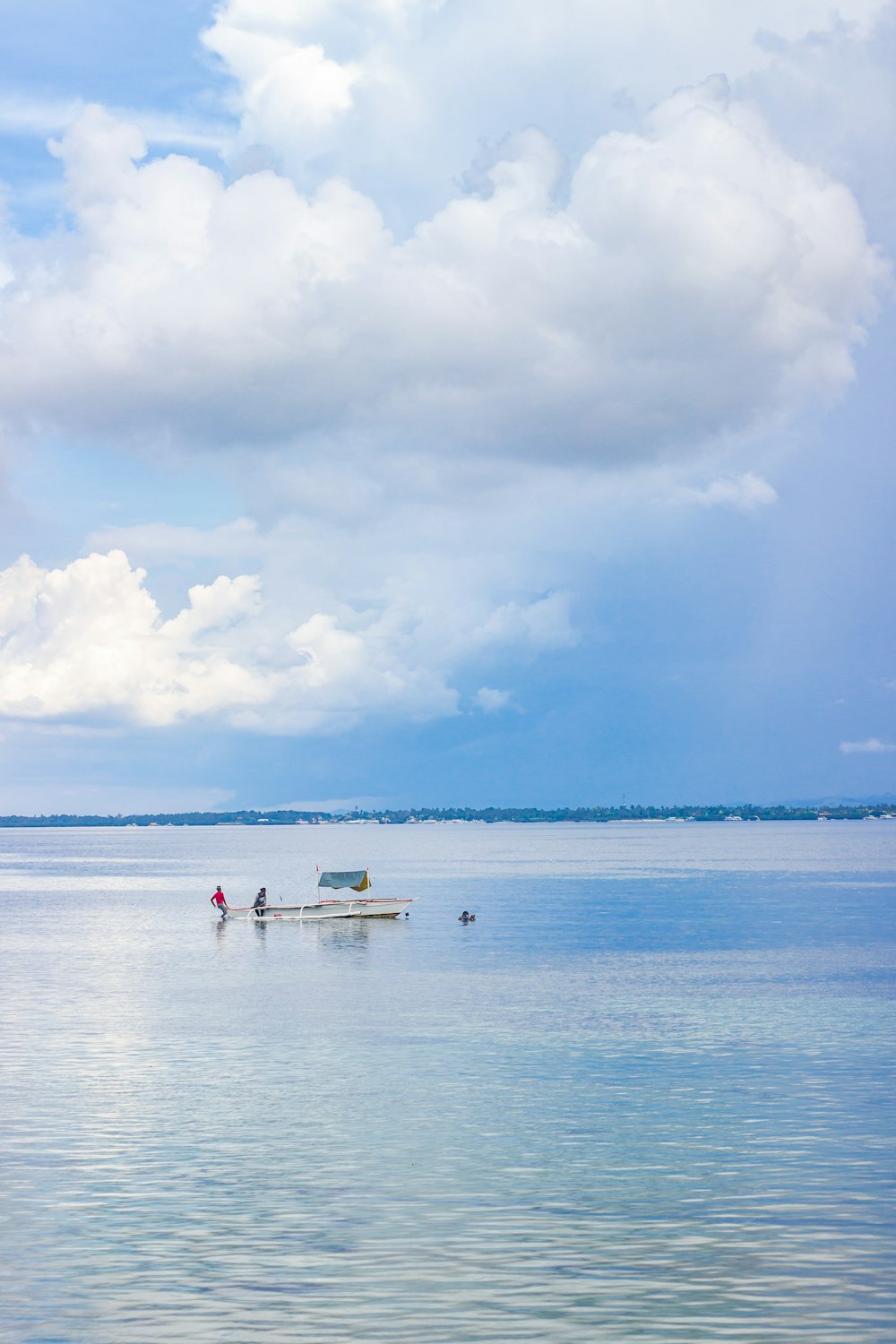 people on white boat on sea under blue sky and white clouds during daytime