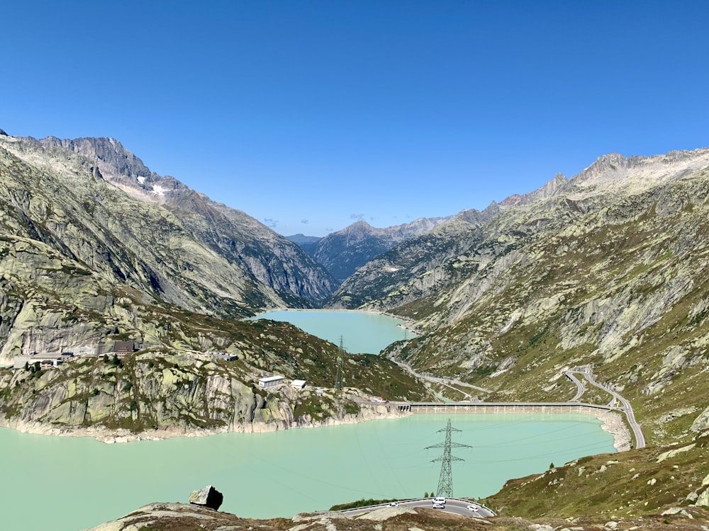 person in black jacket sitting on rock near lake during daytime