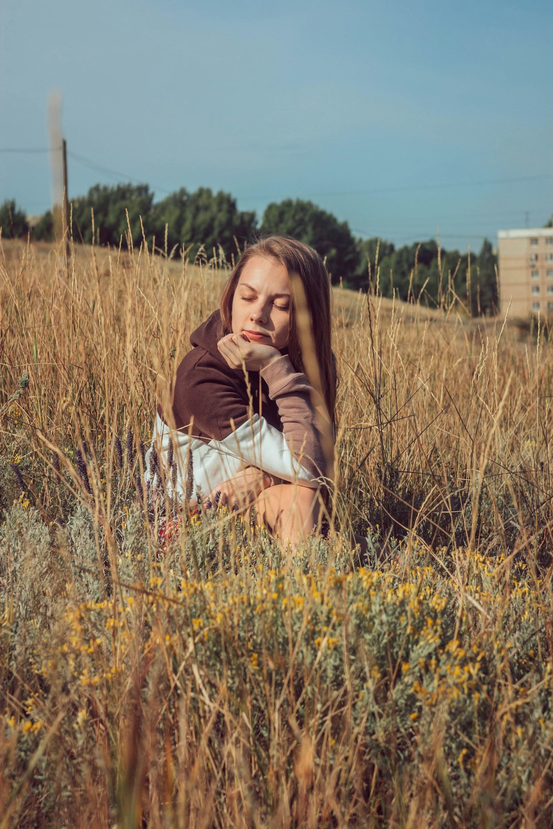 woman in brown long sleeve shirt sitting on brown grass field during daytime