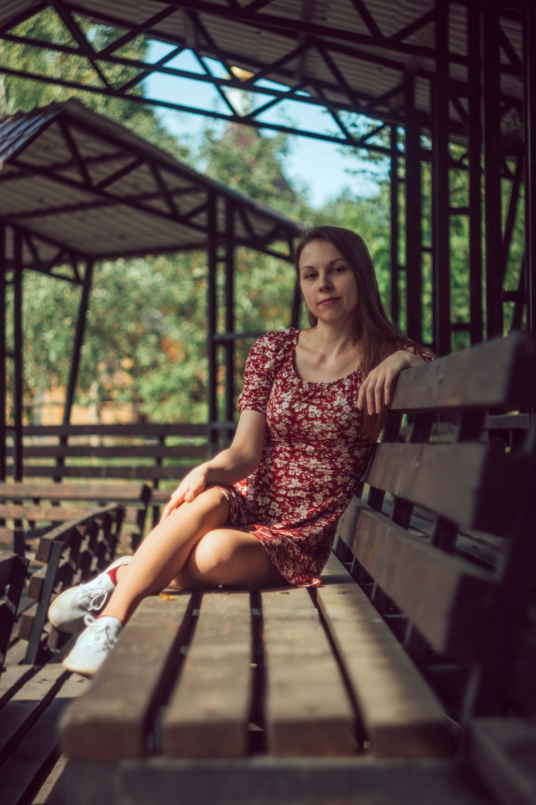woman in black and pink floral dress sitting on brown wooden bench
