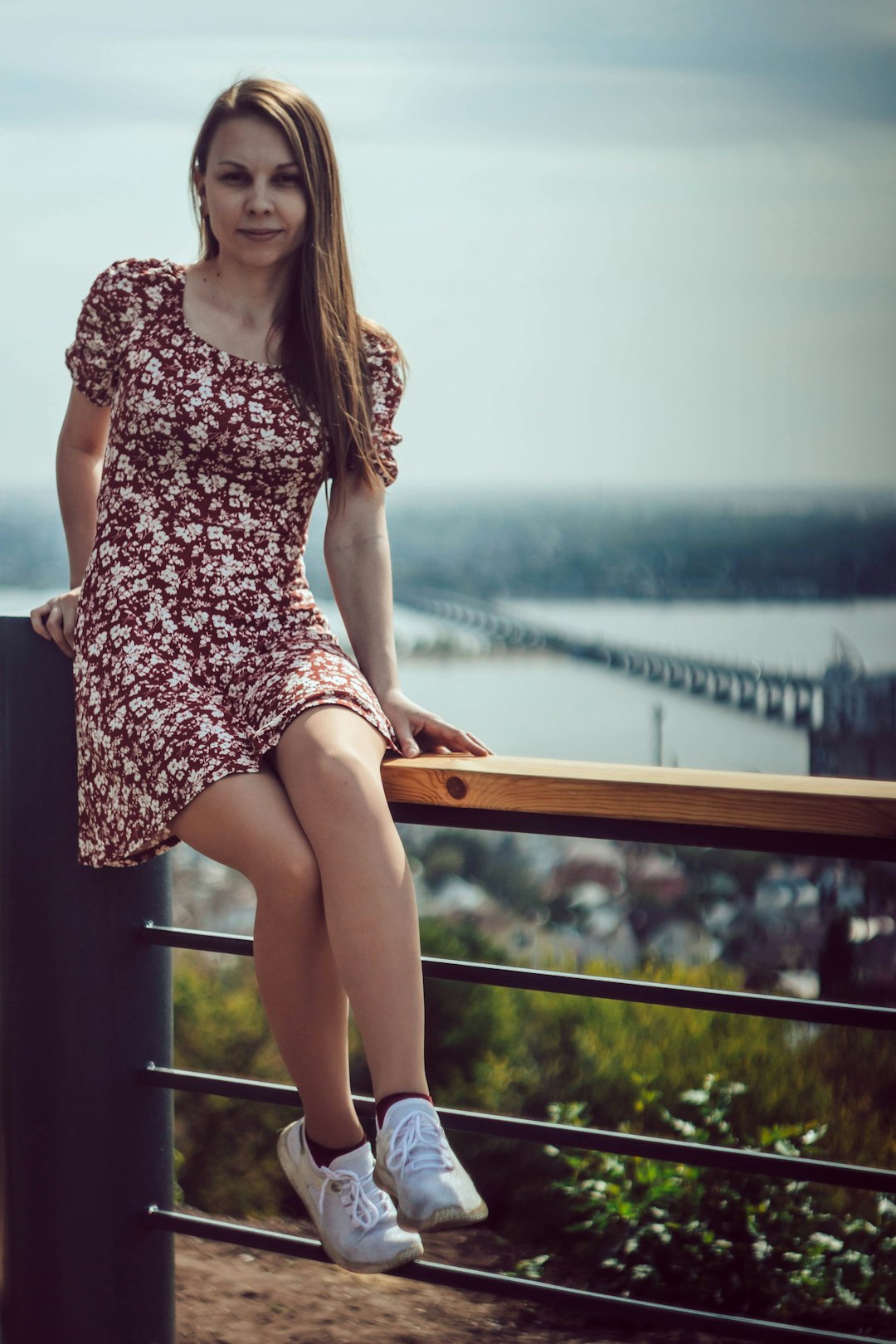 woman in white and black floral dress sitting on brown wooden bench