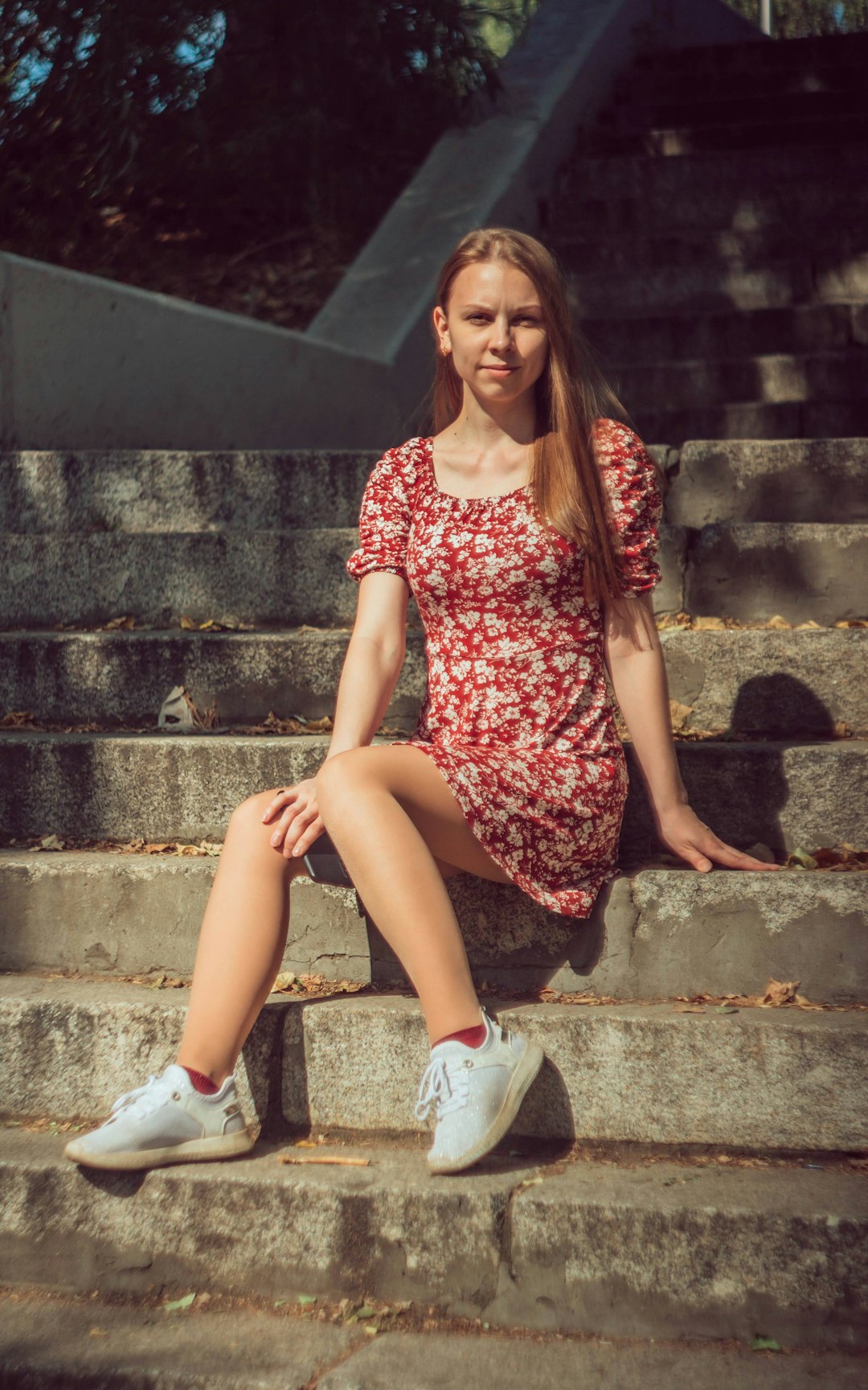 woman in red and white floral dress sitting on stairs
