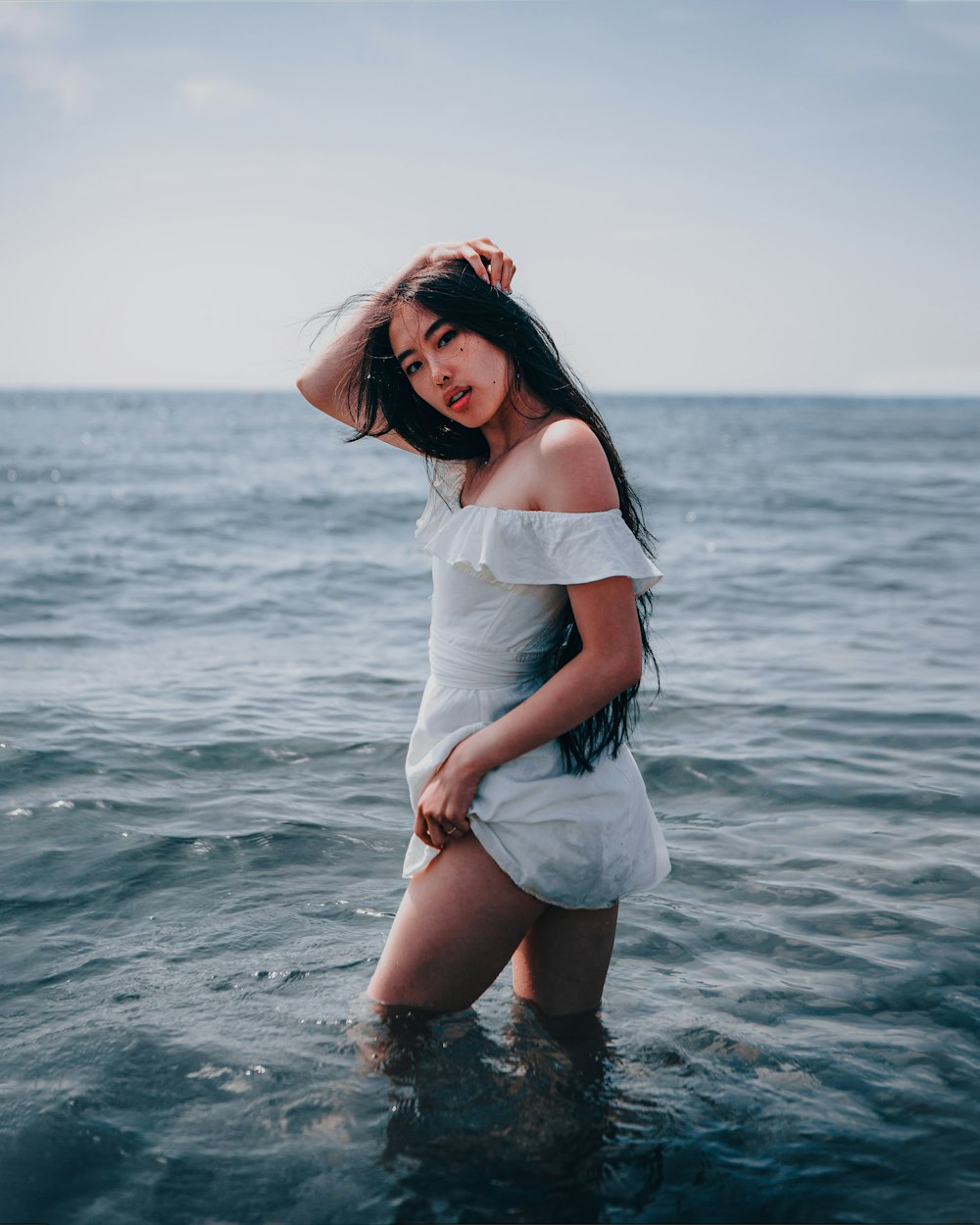 woman in white dress standing on sea water during daytime