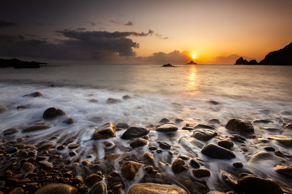 sea waves crashing on shore during sunset