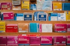 A variety of colorful maps and travel guides are displayed on wooden shelves. The maps are arranged in an orderly manner, with different sizes and titles visible, including Ordnance Survey maps and others for locations like France, Norwich, and Bournemouth.
