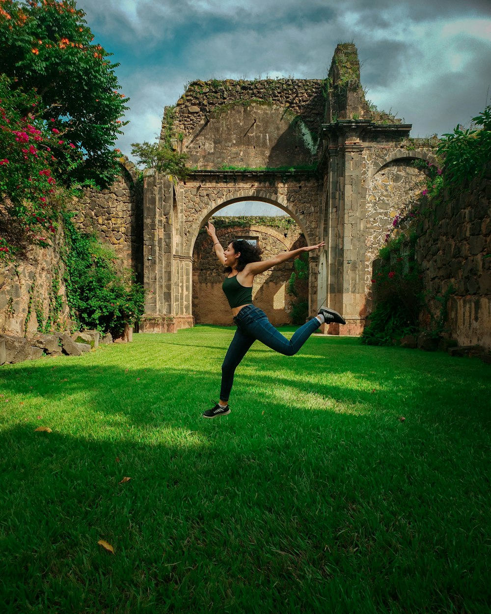 woman in black shirt and black pants jumping on green grass field during daytime