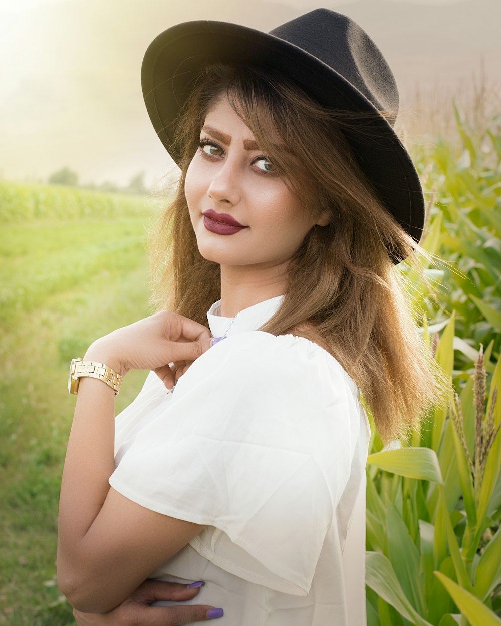 woman in white sleeveless shirt wearing black hat standing on green grass field during daytime