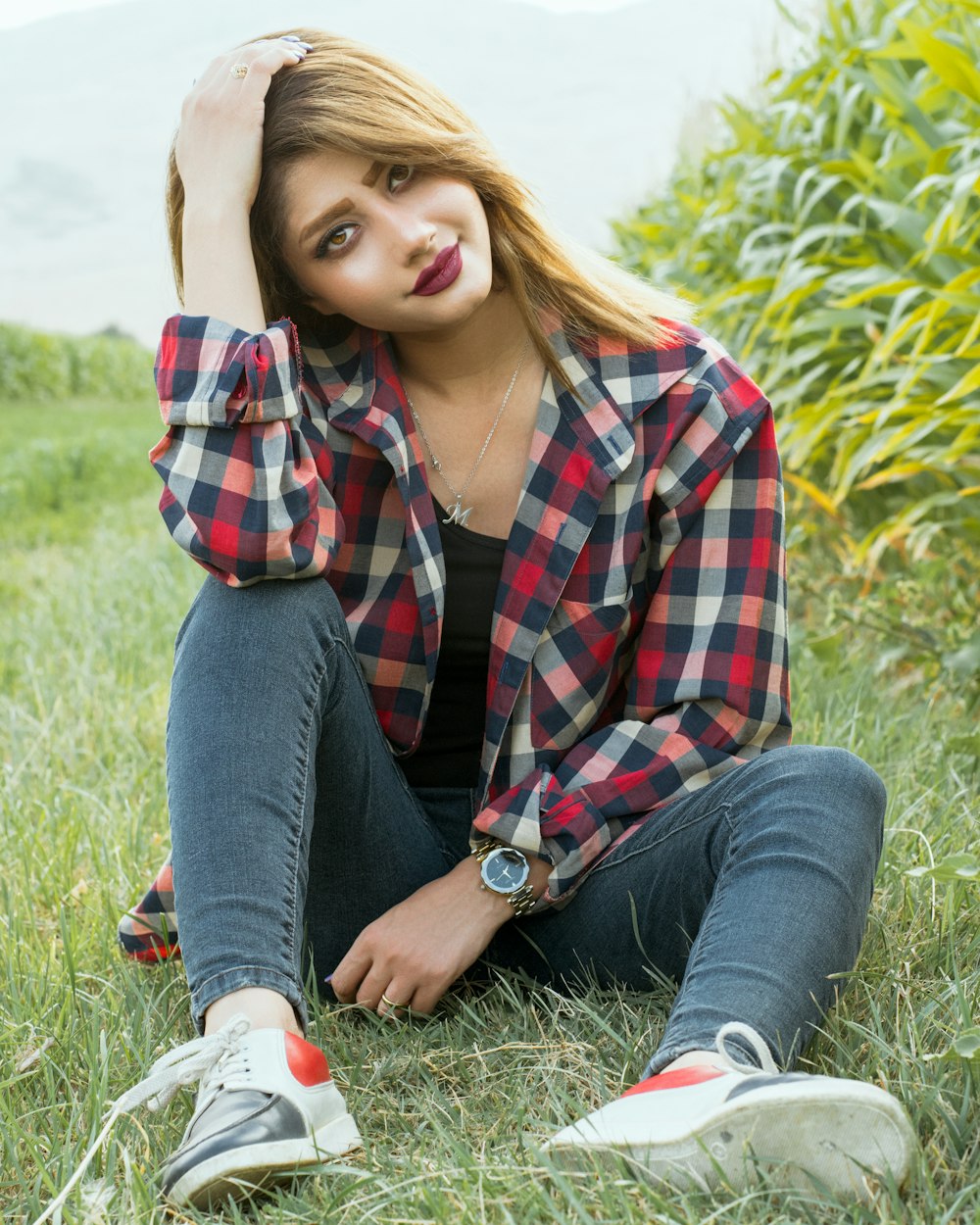 woman in red white and black plaid button up shirt and blue denim jeans sitting on on on on on