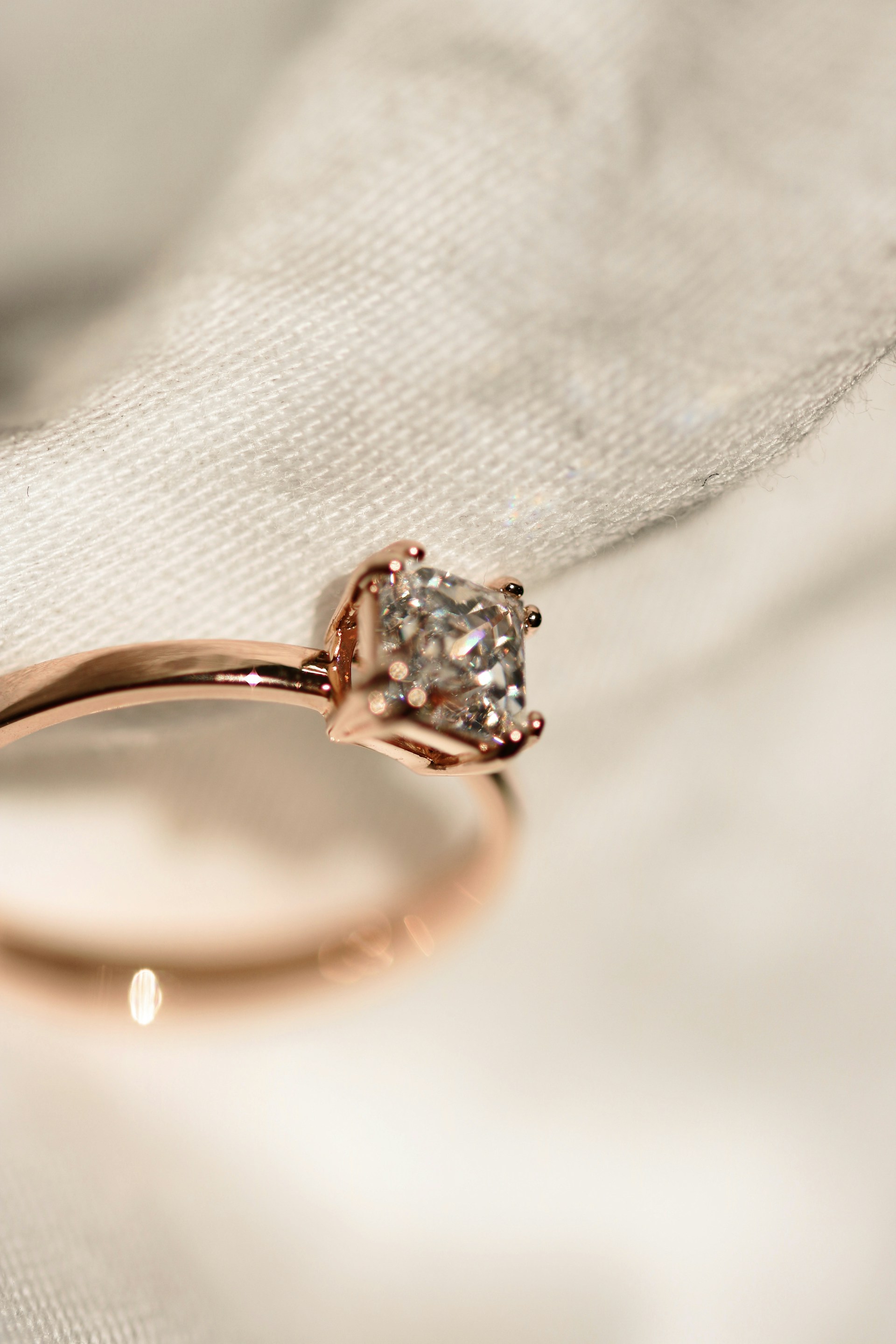 silver diamond ring on white textile