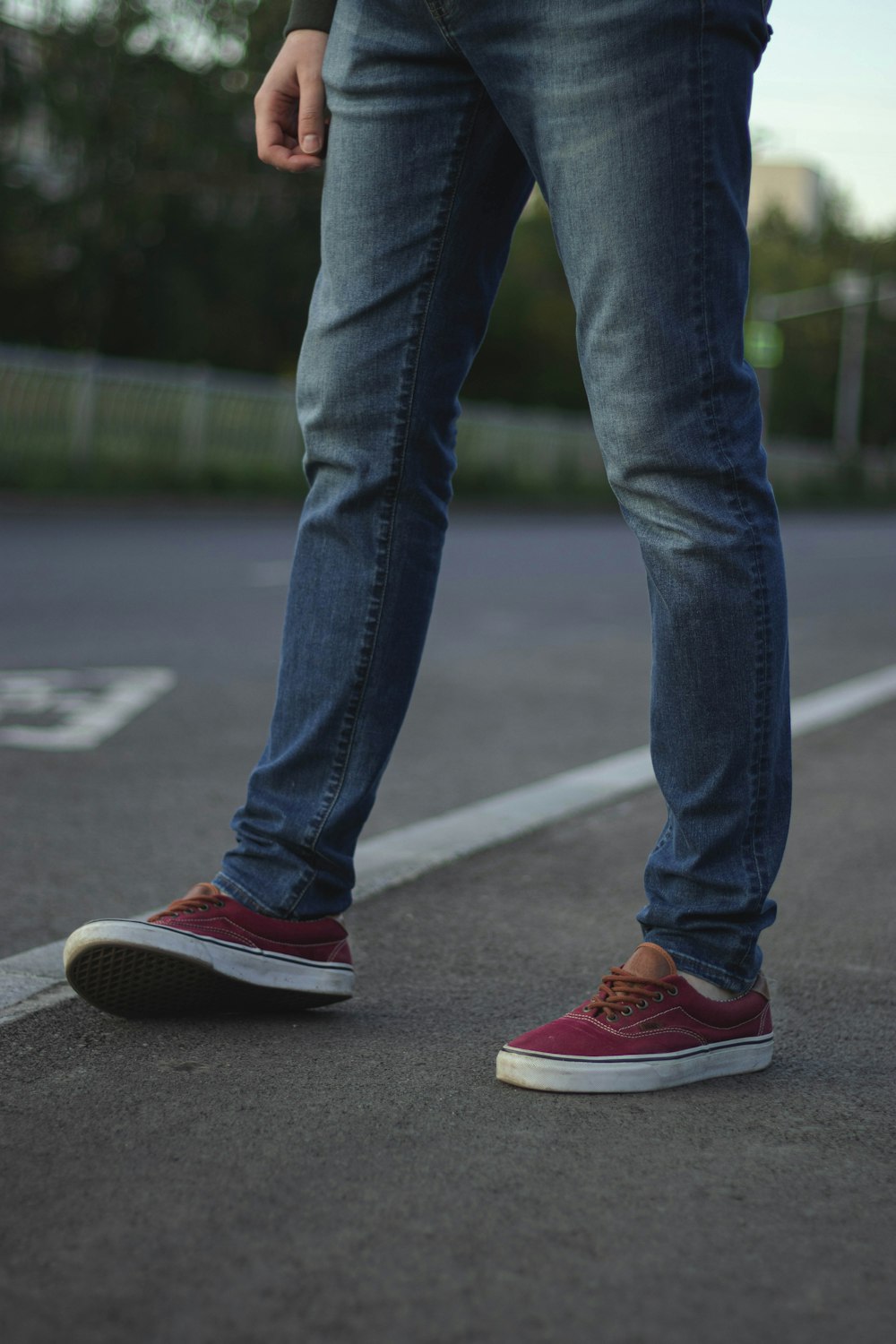 person in blue denim jeans and red nike sneakers