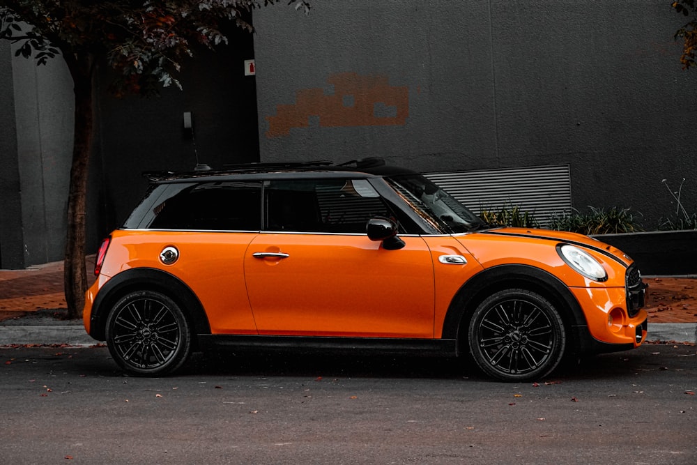 orange car parked beside gray wall