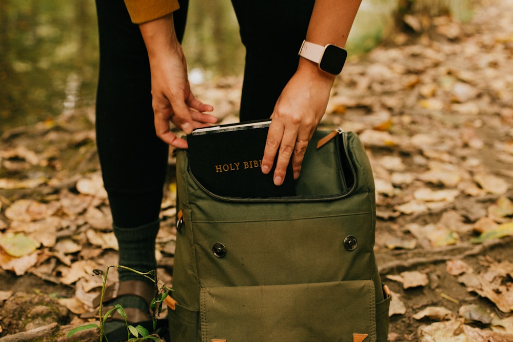 person holding green and black backpack