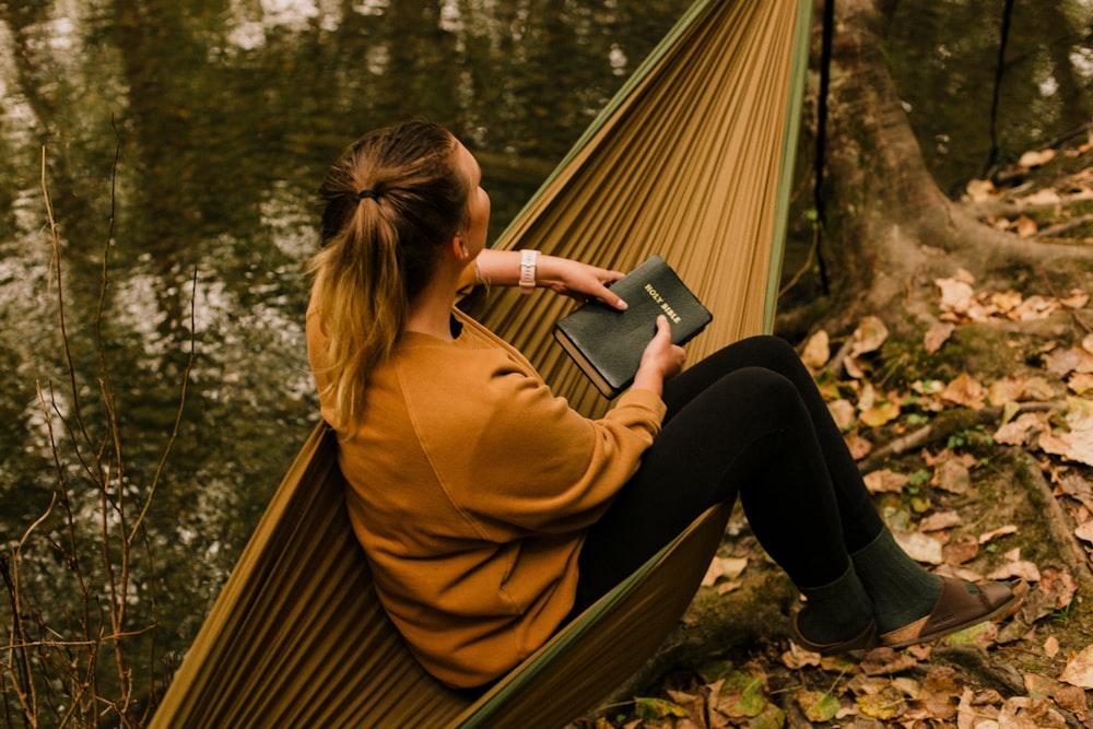 woman in brown coat and black pants sitting on brown wooden bench