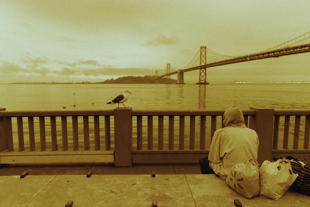 person in brown jacket sitting on brown wooden bench during daytime