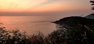 A serene coastal landscape at sunset with soft blue and green hues reflecting on the water