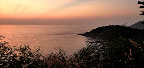 A serene coastal landscape at sunset with soft blue and green hues reflecting on the water