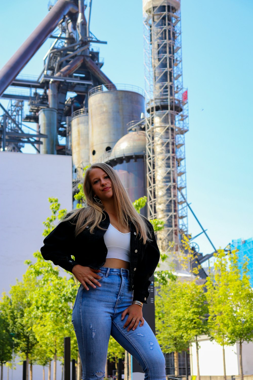 Femme en veste noire et short en jean bleu debout près de la tour blanche pendant la journée