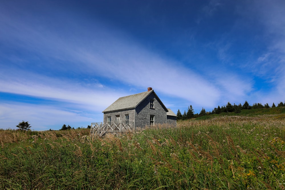 white and black wooden house on green grass field under blue sky during daytime