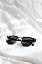 black framed sunglasses on white textile