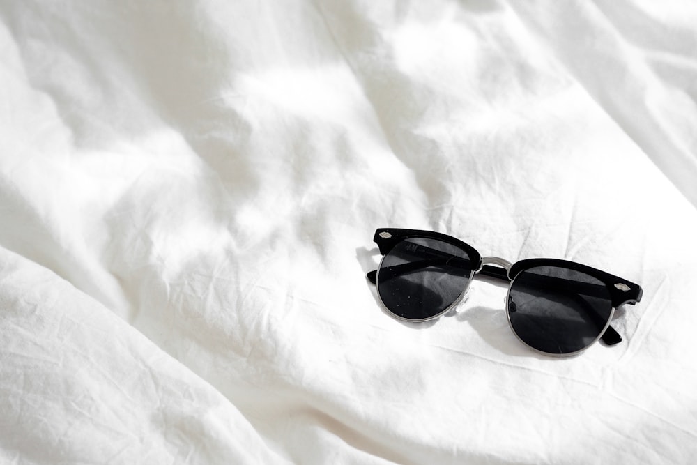 black framed sunglasses on white textile