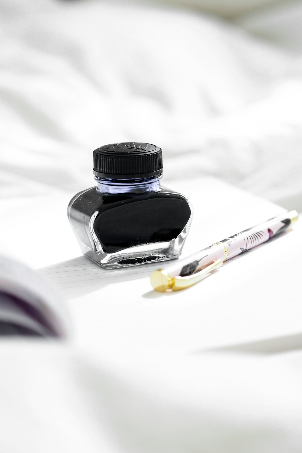 white and yellow click pen beside black glass bottle