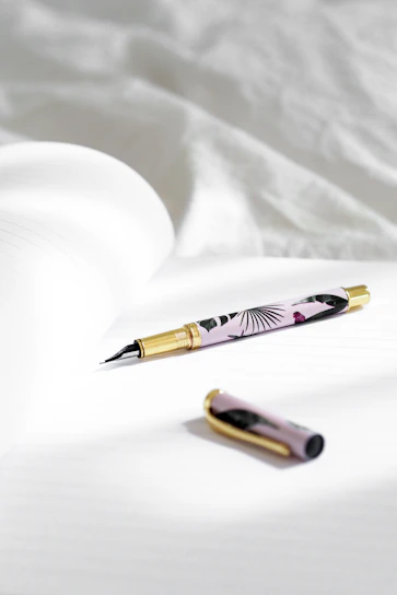 Close-up of a handcrafted fountain pen resting on textured paper with warm natural light.