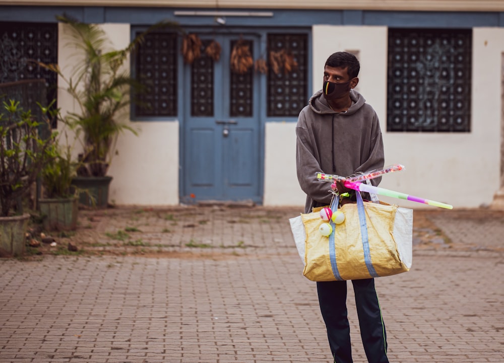 man in gray hoodie holding yellow paper bag