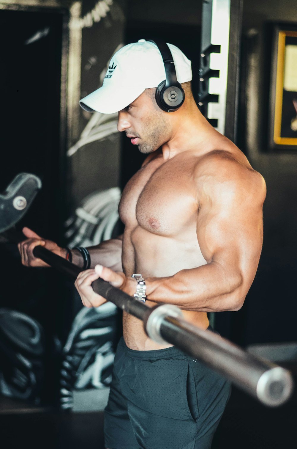 topless man wearing white hat holding black and gray exercise equipment