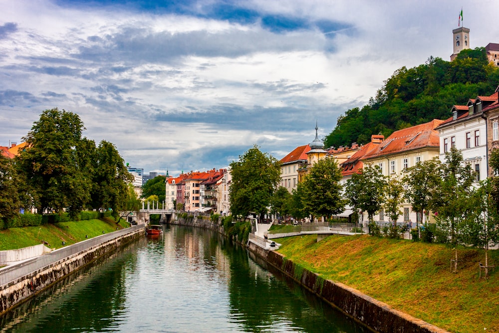 body of water near green trees and houses under cloudy sky during daytime