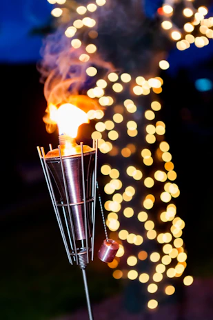 A cozy backyard with erdvėja’s glowing garden torches lighting up a lively evening gathering.